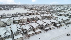 Aerial view of the neighborhood, showcasing a collection of properties featuring various architectural styles, snow-covered roofs, and residential streets - 