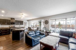 Open concept living area featuring dark wood flooring, recessed lighting, and large sliding glass doors leading to an outdoor deck - 