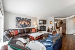 The living area features warm-toned flooring, a fireplace, and a staircase with carpeted treads - 
