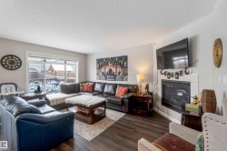 The living area features hard surface flooring, a fireplace with a white mantel, and a large window overlooking the outdoor space - 