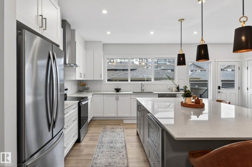 Modern kitchen featuring white cabinetry, stainless steel appliances, a large center island with a light-colored countertop, and recessed lighting - 6127 Carr Road, Edmonton, AB - Indoor Photo Showing Kitchen With Upgraded Kitchen