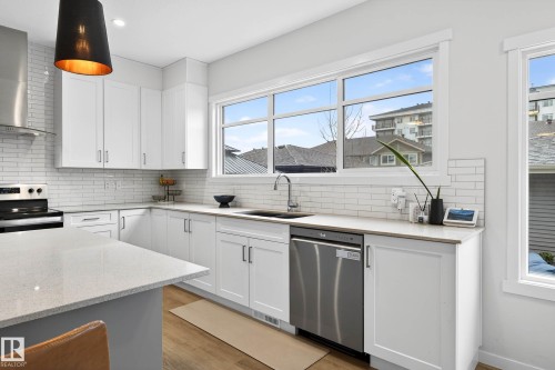 The kitchen features white cabinetry, a white subway tile backsplash, a stainless steel dishwasher, and light-colored countertops - 6127 Carr Road, Edmonton, AB - Indoor Photo Showing Kitchen With Upgraded Kitchen