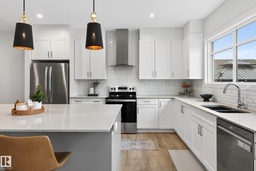The kitchen features white cabinetry, light countertops, and a white subway tile backsplash - 6127 Carr Road, Edmonton, AB - Indoor Photo Showing Kitchen With Double Sink With Upgraded Kitchen