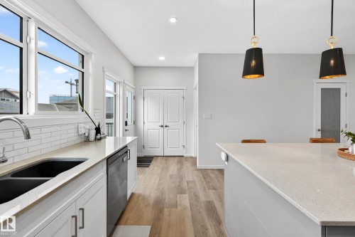 The property features a kitchen with light-colored countertops, a double sink, and white subway tile backsplash, complemented by light-toned flooring - 6127 Carr Road, Edmonton, AB - Indoor Photo Showing Kitchen With Double Sink
