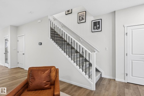 The property features a staircase with a white railing and black metal balusters, complemented by light grey walls and light wood flooring - 6127 Carr Road, Edmonton, AB - Indoor Photo Showing Other Room