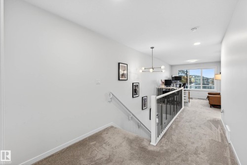 This bright open space features a contemporary chandelier and a window providing natural light - 6127 Carr Road, Edmonton, AB - Indoor Photo Showing Other Room