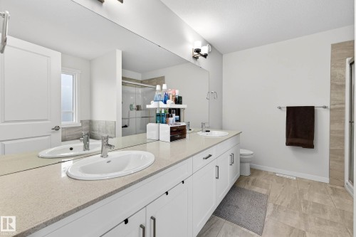 Spacious bathroom featuring a dual vanity with white cabinets, a large mirror, and tiled flooring - 6127 Carr Road, Edmonton, AB - Indoor Photo Showing Bathroom