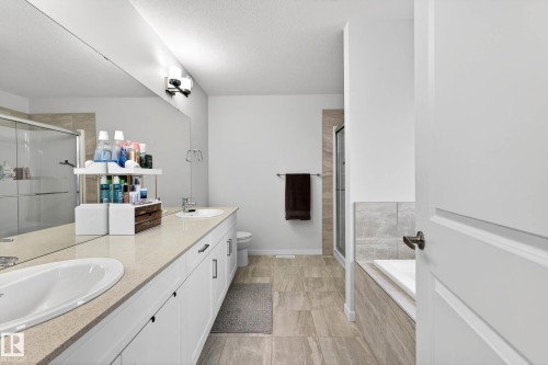 The bathroom features a long vanity with two sinks, a wall-mounted mirror, and a shower with a clear glass enclosure - 6127 Carr Road, Edmonton, AB - Indoor Photo Showing Bathroom