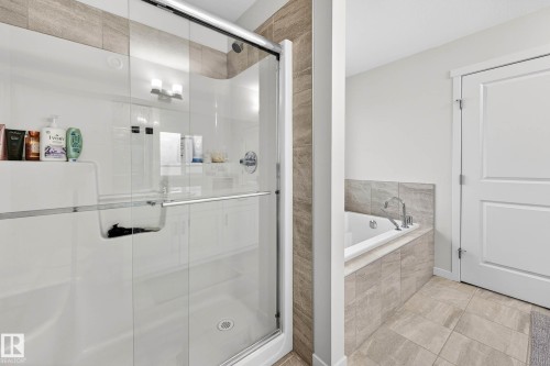 Bathroom featuring a glass-enclosed shower with a built-in bench, and a jetted bathtub with tiled surround - 6127 Carr Road, Edmonton, AB - Indoor Photo Showing Bathroom