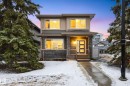 This property features a modern exterior with a mix of siding and brick detailing, illuminated windows, and a welcoming front entrance - 6127 Carr Road, Edmonton, AB  - Outdoor With Facade 