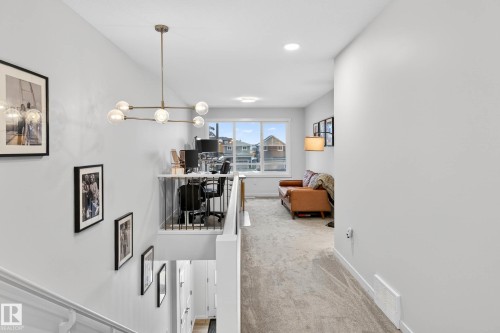 This living area features light gray walls, light gray carpet, and a large window providing natural light - 6127 Carr Road, Edmonton, AB - Indoor Photo Showing Other Room
