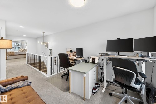 This versatile loft area features light grey carpeting, white walls, and a contemporary light fixture, providing a bright and adaptable space - 6127 Carr Road, Edmonton, AB - Indoor Photo Showing Office