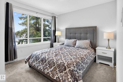 This room features a large window with views of mature trees, light gray walls, and carpet flooring - 6127 Carr Road, Edmonton, AB - Indoor Photo Showing Bedroom