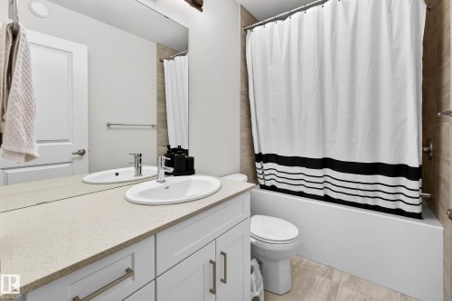 Bathroom featuring a vanity with a light-colored countertop and white cabinetry, a bathtub with a shower, and light-colored floor tiles - 6127 Carr Road, Edmonton, AB - Indoor Photo Showing Bathroom