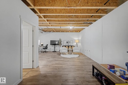 This spacious room features light-toned wood flooring, exposed ceiling joists, and white walls - 6127 Carr Road, Edmonton, AB - Indoor Photo Showing Other Room