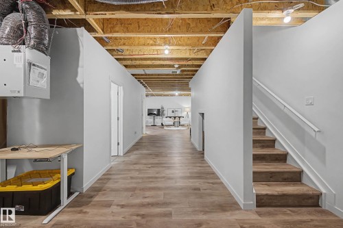Finished basement area featuring wood-look flooring, light gray walls, and exposed ceiling joists - 6127 Carr Road, Edmonton, AB - Indoor Photo Showing Other Room
