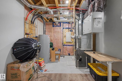 The property features a utility area with exposed ceiling joists, ductwork, plumbing, and a water heater - 6127 Carr Road, Edmonton, AB - Indoor Photo Showing Basement