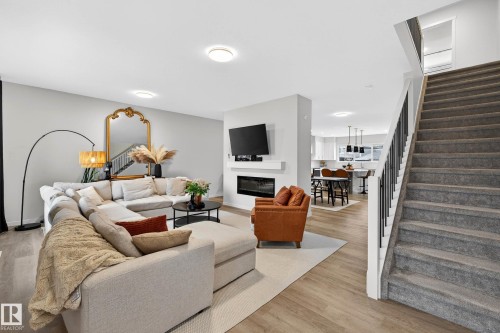 Spacious living room featuring light-toned flooring and a built-in fireplace - 6127 Carr Road, Edmonton, AB - Indoor Photo Showing Living Room With Fireplace