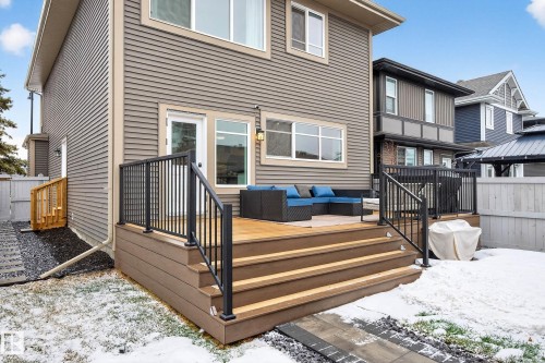 The property features a spacious rear deck with black railings, accessible via exterior stairs, and a ground-level patio area - 6127 Carr Road, Edmonton, AB - Outdoor With Deck Patio Veranda With Exterior