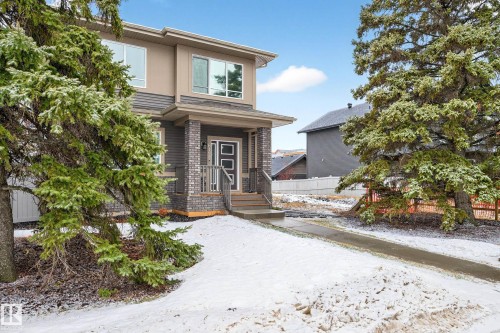The property features a modern exterior with a mix of siding and brick accents, a covered front porch, and mature evergreen trees - 6127 Carr Road, Edmonton, AB - Outdoor