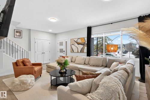 Living area featuring light-toned flooring, a light-colored area rug, and large windows providing natural light - 6127 Carr Road, Edmonton, AB - Indoor Photo Showing Living Room