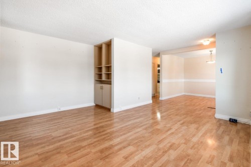 The property features light-toned flooring throughout, with a built-in shelving unit, and overhead lighting fixtures - 7324 77 Street, Edmonton, AB - Indoor Photo Showing Other Room