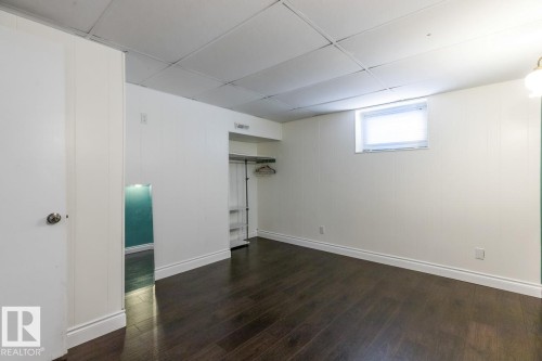 This room features dark wood flooring, white paneled walls, and a drop ceiling - 7324 77 Street, Edmonton, AB - Indoor