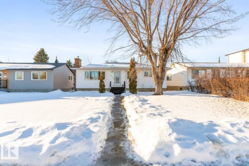 The property features a white exterior, a front yard, and a paved walkway leading to the entrance - 7324 77 Street, Edmonton, AB - Outdoor