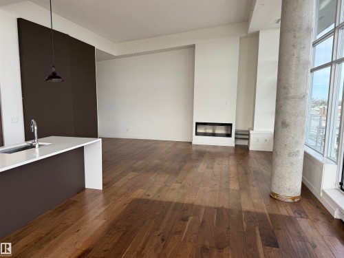 This spacious room features rich hardwood flooring, a modern fireplace, and large windows that provide abundant natural light and exterior views - 710 2504 109 Street, Edmonton, AB - Indoor