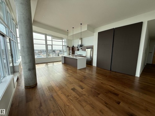 Expansive living area featuring hardwood flooring, abundant natural light from large windows, and a modern kitchen with a center island and stainless steel appliances - 710 2504 109 Street, Edmonton, AB - Indoor