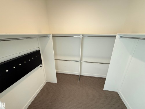 The property features a closet with built-in shelving, hanging rods, and carpeted flooring - 710 2504 109 Street, Edmonton, AB - Indoor With Storage