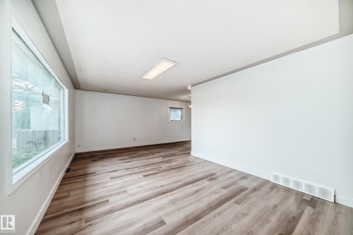 Spacious room featuring light wood-look flooring, white walls, and a large window - 9126 152 St, Edmonton, AB - Indoor Photo Showing Other Room