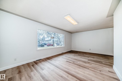 This room features hardwood style flooring, a large window providing natural light, and a ceiling-mounted light fixture - 9126 152 St, Edmonton, AB - Indoor Photo Showing Other Room
