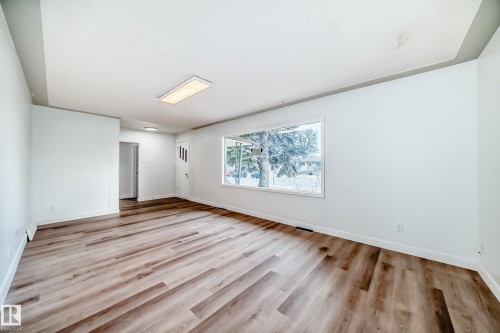 This inviting living space features light wood-style flooring, a large window providing views of the outdoors, and a contemporary ceiling light fixture - 9126 152 St, Edmonton, AB - Indoor Photo Showing Other Room