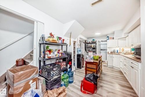 The property features a kitchen with white cabinetry and light-toned flooring, along with a visible washer and dryer - 9126 152 St, Edmonton, AB - Indoor