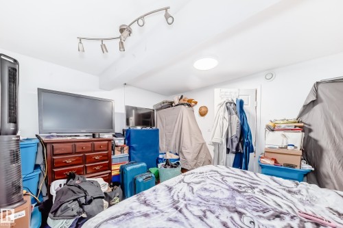 This room features white walls and ceiling, with a track lighting fixture and a flush-mount ceiling light - 9126 152 St, Edmonton, AB - Indoor Photo Showing Bedroom