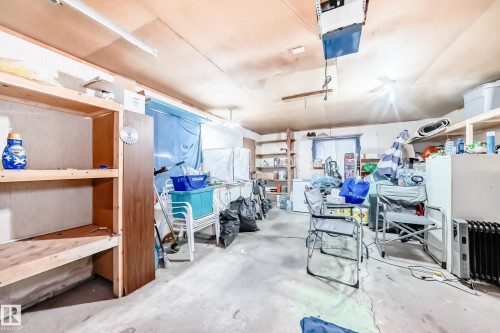 The garage features concrete flooring, built-in wooden shelving, and an overhead garage door opener - 9126 152 St, Edmonton, AB - Indoor Photo Showing Garage