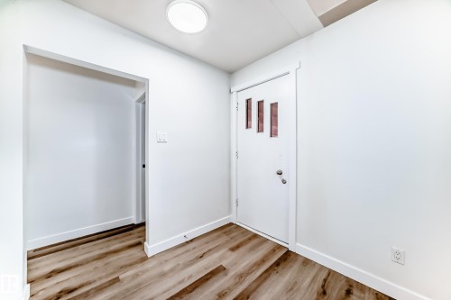 The entryway features a modern front door with decorative vertical window inserts, light-toned wood-look flooring, and a circular overhead light fixture - 9126 152 St, Edmonton, AB - Indoor Photo Showing Other Room