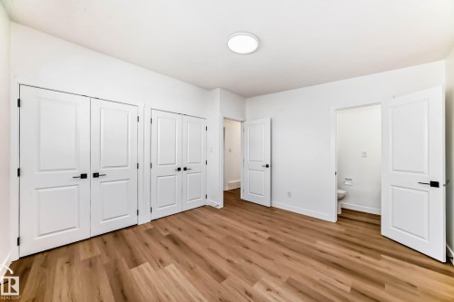 Bright room featuring light-toned wood flooring, white walls, and white paneled doors with black hardware - 7220 152A Ave, Edmonton, AB - Indoor Photo Showing Other Room