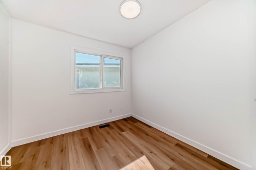 This room features light wood-style flooring, white walls, and a window providing natural light - 7220 152A Ave, Edmonton, AB - Indoor Photo Showing Other Room