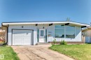 The property features a white exterior with vertical siding, a white garage door, and a white front entry door with a sidelight - 7220 152A Ave, Edmonton, AB  - Outdoor 