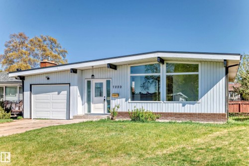 The property features a white exterior with a contrasting dark trim, a front-facing garage with a white door, and large windows - 7220 152A Ave, Edmonton, AB - Outdoor
