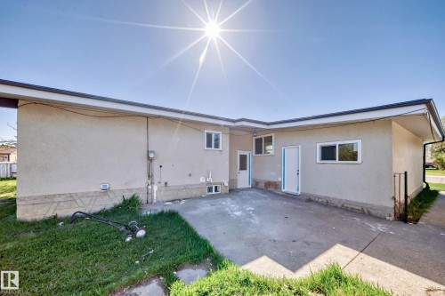 The property features a stucco exterior with multiple windows and doors, and a concrete patio area - 7220 152A Ave, Edmonton, AB - Outdoor With Exterior