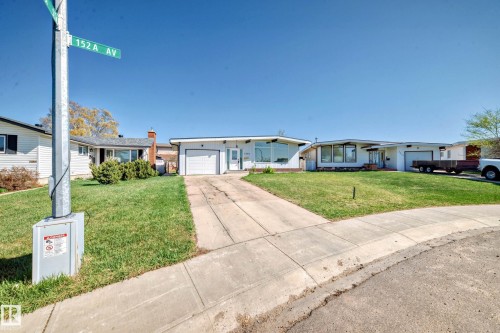 The property features a white exterior, an integrated garage, and a well-maintained front lawn - 7220 152A Ave, Edmonton, AB - Outdoor
