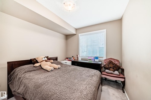 Bedroom featuring a window with blinds, carpeted flooring, and a ceiling light fixture - 116 5810 Mullen Place, Edmonton, AB - Indoor Photo Showing Bedroom