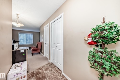 Hallway featuring tile flooring, neutral wall paint, and white bifold doors - 116 5810 Mullen Place, Edmonton, AB - Indoor Photo Showing Other Room