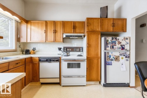 Functional kitchen featuring wood-finish cabinetry, white countertops, a window with blinds, and tile backsplash - 13437 118 Street, Edmonton, AB - Indoor Photo Showing Kitchen