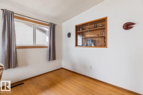 Hardwood flooring throughout featuring a wall-mounted display cabinet with glass doors - 13437 118 Street, Edmonton, AB - Indoor Photo Showing Other Room