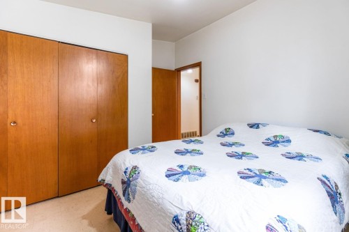 Wood-finish bi-fold closet doors provide ample storage - 13437 118 Street, Edmonton, AB - Indoor Photo Showing Bedroom