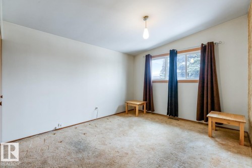 Bright room featuring dual windows with natural wood trim, white walls, and a sloped ceiling with a pendant light fixture - 13437 118 Street, Edmonton, AB - Indoor Photo Showing Other Room